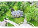 Aerial view of a brick house with lush landscaping, a circular driveway, and mature trees at 3772 Christina Ct, Carmel, IN 46033