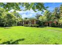 Spacious single-story home featuring a lush green lawn and mature trees at 415 Woodhill Dr, Indianapolis, IN 46227