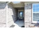 Covered front entrance featuring brick siding and a storm door at 5196 Canberra Ct, McCordsville, IN 46055