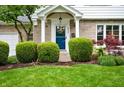 Inviting front entrance with a vibrant blue door, decorative wreath, and meticulously maintained landscaping at 6020 Gladden Dr, Indianapolis, IN 46220