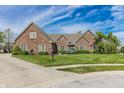 Charming brick home showcasing a lush lawn and mature landscaping at 7093 Republic Ln, Indianapolis, IN 46259