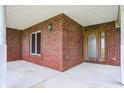 Inviting covered porch featuring brick walls, a light fixture, and a beautiful wooden front door at 7333 State Road 42, Martinsville, IN 46151