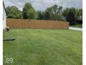 Spacious backyard featuring lush green grass and a tall wooden fence for added privacy at 8123 Summertree Ct, Indianapolis, IN 46256