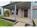 View of the porch showing its brick and grey pillar design, front door, and trimmed flower bed at 9206 Huntleigh Cir, Plainfield, IN 46168