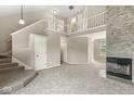 Expansive living room featuring a soaring ceiling, a stone fireplace, plush carpeting, and a staircase to the second floor at 11072 Lake Run Dr, Fishers, IN 46038