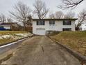 Charming two-story white home featuring an attached garage and a long driveway leading up to the property at 1325 Northcrest Dr, Anderson, IN 46012