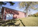 Side view of the large red outbuilding or barn with a white door and blue service door at 13518 Promise Rd, Fishers, IN 46038