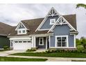 Charming home featuring blue siding, a brown roof, a white garage door and beautifully landscaped front yard at 15596 Edenvale Dr, Westfield, IN 46074