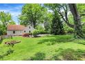Expansive backyard featuring lush green grass, mature trees, and a charming fire pit area at 1725 W 53Rd St, Indianapolis, IN 46228