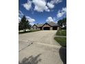 Charming brick home with a spacious driveway, two car garage, well-manicured lawn, and flagpole under a bright, partly cloudy sky at 28 Patriot Ct, Greenfield, IN 46140