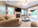 Comfortable living room with a fireplace, mounted TV, and an open layout flowing into the sunroom at 2875 Prairie Stream Way, Columbus, IN 47203