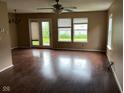 Bright living room featuring wood floors, a ceiling fan, and natural light from large windows and a sliding glass door at 4456 Redcliff N Ln, Plainfield, IN 46168