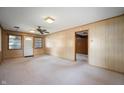Open living room with wood-paneled walls, ceiling fan, and neutral carpeting at 924 N Devon Ave, Indianapolis, IN 46219