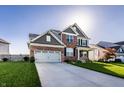 Attractive two-story home featuring a brick facade, a two-car garage, and a spacious driveway, with an inviting appeal at 1065 Park Ct, Avon, IN 46123