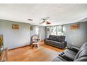 Bright living room with hardwood floors, comfortable seating, ceiling fan, and decorative wall art at 10758 W State Road 142, Quincy, IN 47456