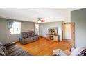 Comfortable living room with a plush reclining sofa, hardwood floors, ceiling fan, and natural light from the window at 10758 W State Road 142, Quincy, IN 47456