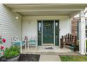 Covered front porch featuring a dark green front door, seating, and lush potted plants at 12524 Trophy Dr, Fishers, IN 46038