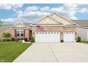 Charming brick home featuring an attached two car garage, manicured lawn, and an American flag at 1468 Blackthorne N Trl, Plainfield, IN 46168