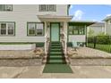Inviting front porch with potted plants, green-carpeted steps, and an accent chair at 236 W 33Rd St, Indianapolis, IN 46208