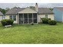 Home's backyard featuring a screened in porch and a large green lawn at 540 Cahill Ln, Indianapolis, IN 46214
