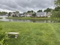 Scenic backyard view of a tranquil pond surrounded by lush greenery and neighboring homes at 540 Cahill Ln, Indianapolis, IN 46214