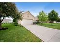 A well-kept one story brick home with lush green lawn, mature trees, and a spacious driveway leading to the garage at 5576 W Glenview Dr, McCordsville, IN 46055