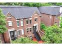 A rear view of brick townhomes with private outdoor stairways and a view of the surrounding lush greenery at 558 E Vermont St, Indianapolis, IN 46202