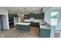 A modern kitchen featuring stylish green cabinetry, an island, and stainless steel appliances at 6450 Stone Side Dr, Plainfield, IN 46168