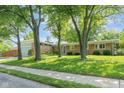 Charming single-story home with stone accents, lush lawn, mature trees, and a pop of color at the front door at 650 W Main St, Carmel, IN 46032