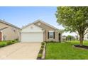 Inviting single-story home features a well-kept lawn, attached garage and neutral exterior paint at 671 Greenway St, Greenwood, IN 46143