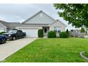 Charming single-story home with a well-maintained lawn, blue car and truck in driveway, and attractive landscaping at 7515 Brattle Dr, Indianapolis, IN 46113