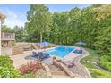 Inviting backyard pool area with comfortable seating, blue umbrellas, beautiful landscaping and wooded backdrop at 790 Foxboro Dr, Avon, IN 46123