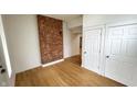 Bright bedroom with hardwood floors, exposed brick accent wall, and closet at 909 N Temple Ave, Indianapolis, IN 46201