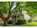 Charming two-story home with a cozy front porch and mature trees, providing a welcoming curb appeal at 925 Fayette St, Indianapolis, IN 46202