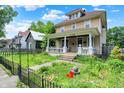 Inviting two-story home with a classic front porch, surrounded by lush greenery and a well-manicured lawn at 1138 N Oxford St, Indianapolis, IN 46201