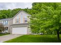 Two-story home with light siding, a two-car garage, manicured lawn, and mature trees at 11919 Gatwick View Dr, Fishers, IN 46037