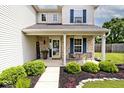 Inviting front porch with brick accents, plants, and seating area at 1222 Grand Canyon Ct, Franklin, IN 46131