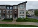 Stylish townhome exterior showcasing brick and stone accents, complemented by lush green landscaping at 12908 Grand Blvd, Carmel, IN 46032
