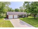 Charming ranch home with brick accents, mature trees, a two-car garage, and a wide driveway at 1308 N Main St, Lapel, IN 46051