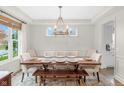 Formal dining area with modern chandelier over wood table, seating for eight, and decorative window at 14931 W Black Wolf Run Dr, Carmel, IN 46033
