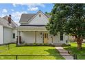Exterior shot of a house featuring a covered front porch, bright yellow door and green lawn at 1627 Pleasant St, Indianapolis, IN 46203