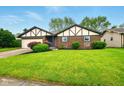 Inviting front of brick home with green lawn, landscaped beds, and blue front door at 4701 Candy Spots Dr, Indianapolis, IN 46237