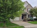 Attractive two-story home boasts a brick facade, attached garage, and a well-maintained lawn with lush greenery at 5305 Potomac Ln, Greenwood, IN 46142
