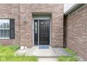 Close-up of a black front door with brick facade, window, and welcome mat at 65 Millet Ct, Danville, IN 46122