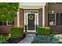 Inviting front entrance with brick facade, columns, flower pots, and decorative wreath at 6649 Braemar S Ave, Noblesville, IN 46062
