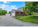 Side view of brick home and detached garage with long driveway, beautiful lawn, and professional landscaping at 6838 Five Points Rd, Indianapolis, IN 46259