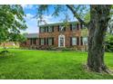 Attractive two-story brick home featuring a lush front lawn with shade trees and a well maintained garden at 6838 Five Points Rd, Indianapolis, IN 46259