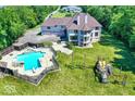 Aerial view of a backyard with a large pool, playset, and a beautiful yard with many trees at 11575 Freeport Dr, Carmel, IN 46032
