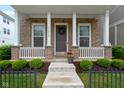 Charming front porch with brick columns, decorative wreath, and potted flowers, enhanced by green bushes at 13048 Minden Dr, Fishers, IN 46037