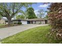 Charming single-story home with stone accents, a spacious driveway, and lush green lawn at 1311 N Eaton Ave, Indianapolis, IN 46219